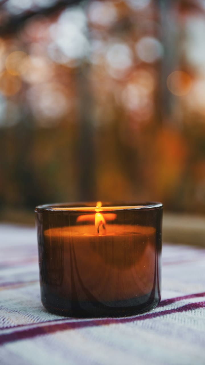 A plain product photo of an amber glass candle on a striped cloth